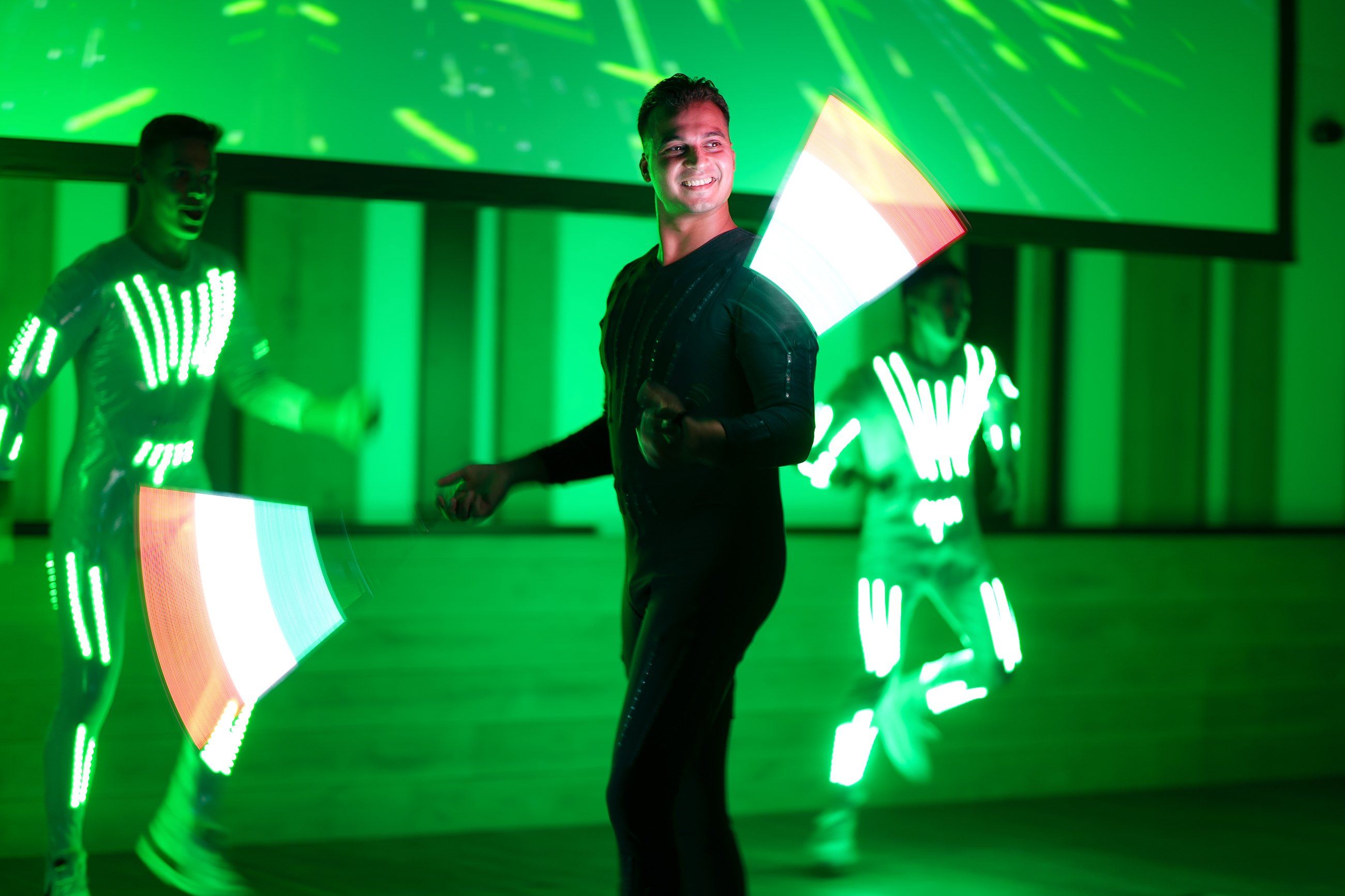 LED-suited performers on a green-lit stage