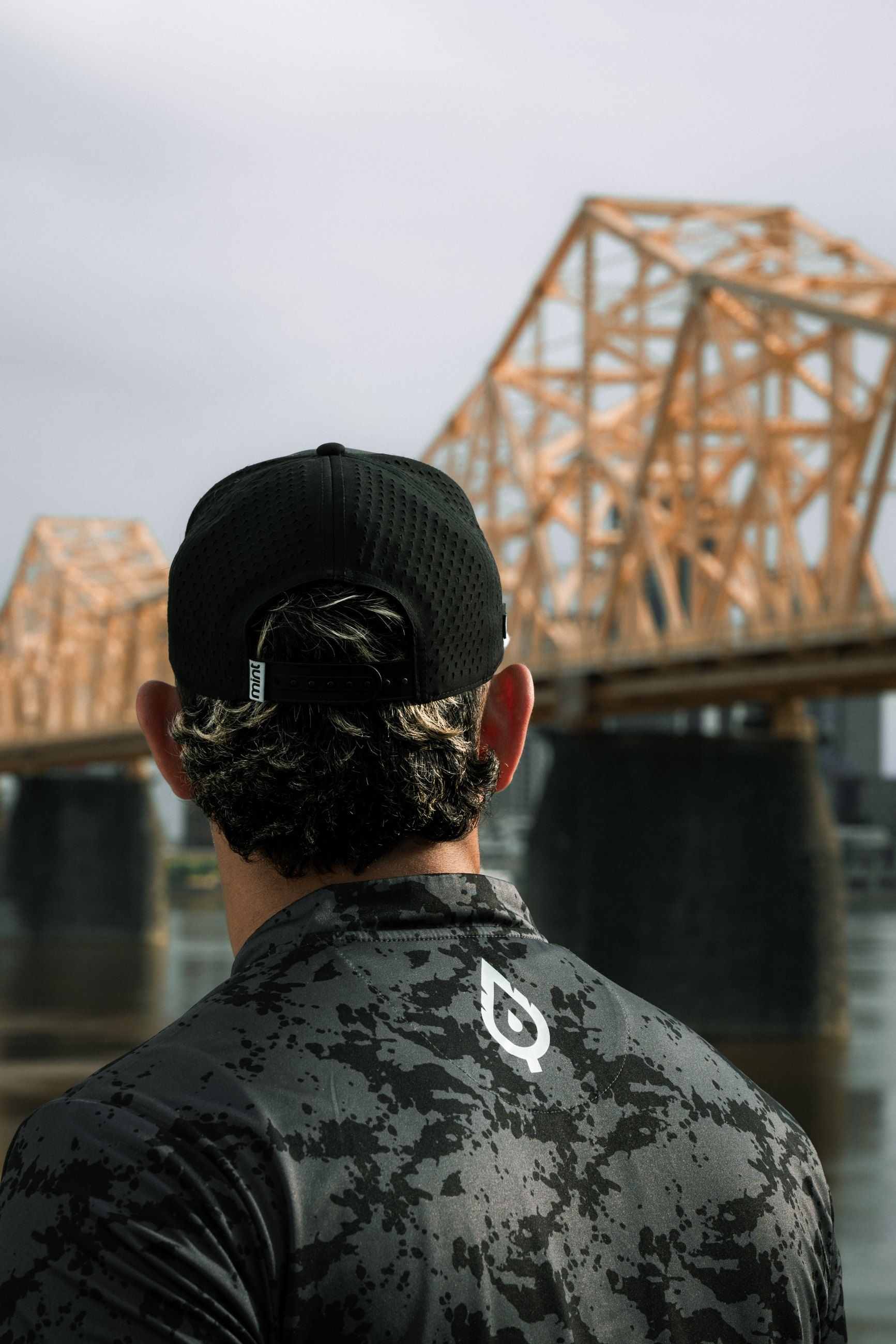 Technician seen from behind, facing an orange steel bridge