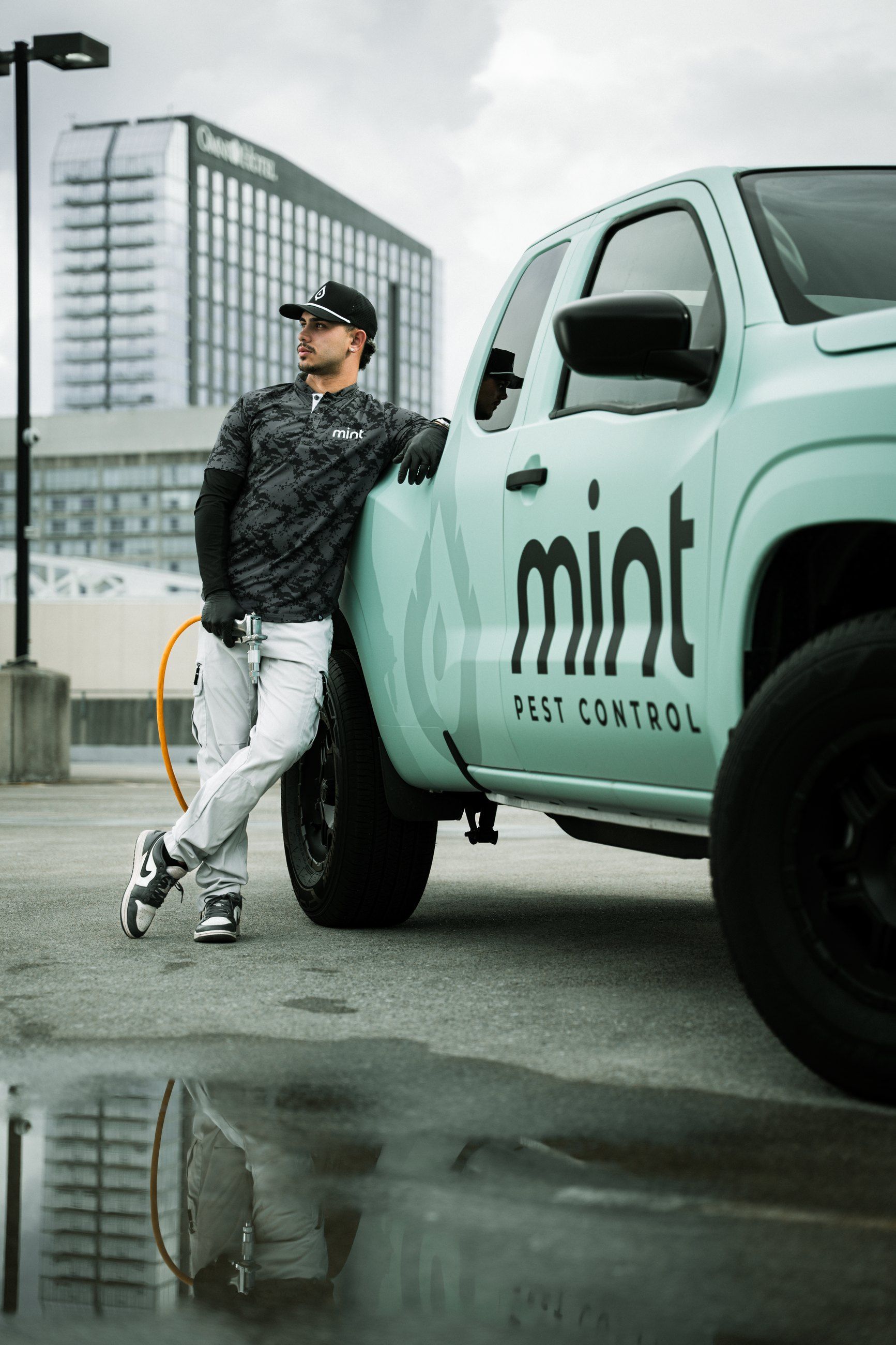 Technician leaning on a mint-green service truck on a wet rooftop