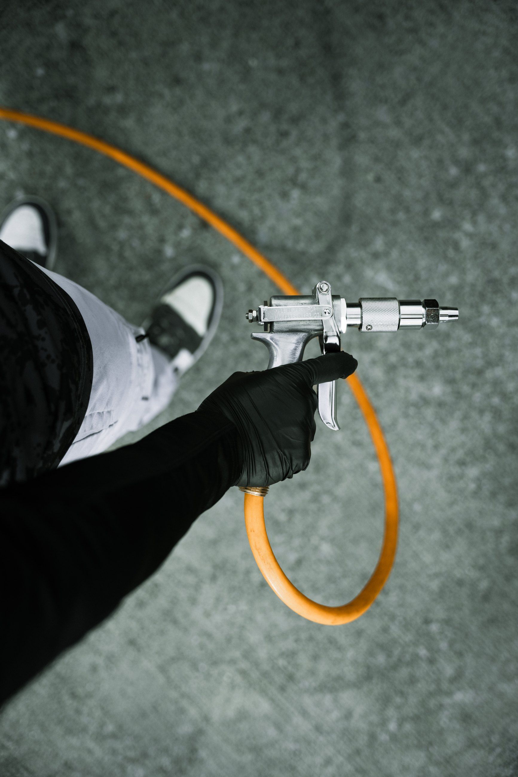 Gloved hand holding a spray gun on an orange hose
