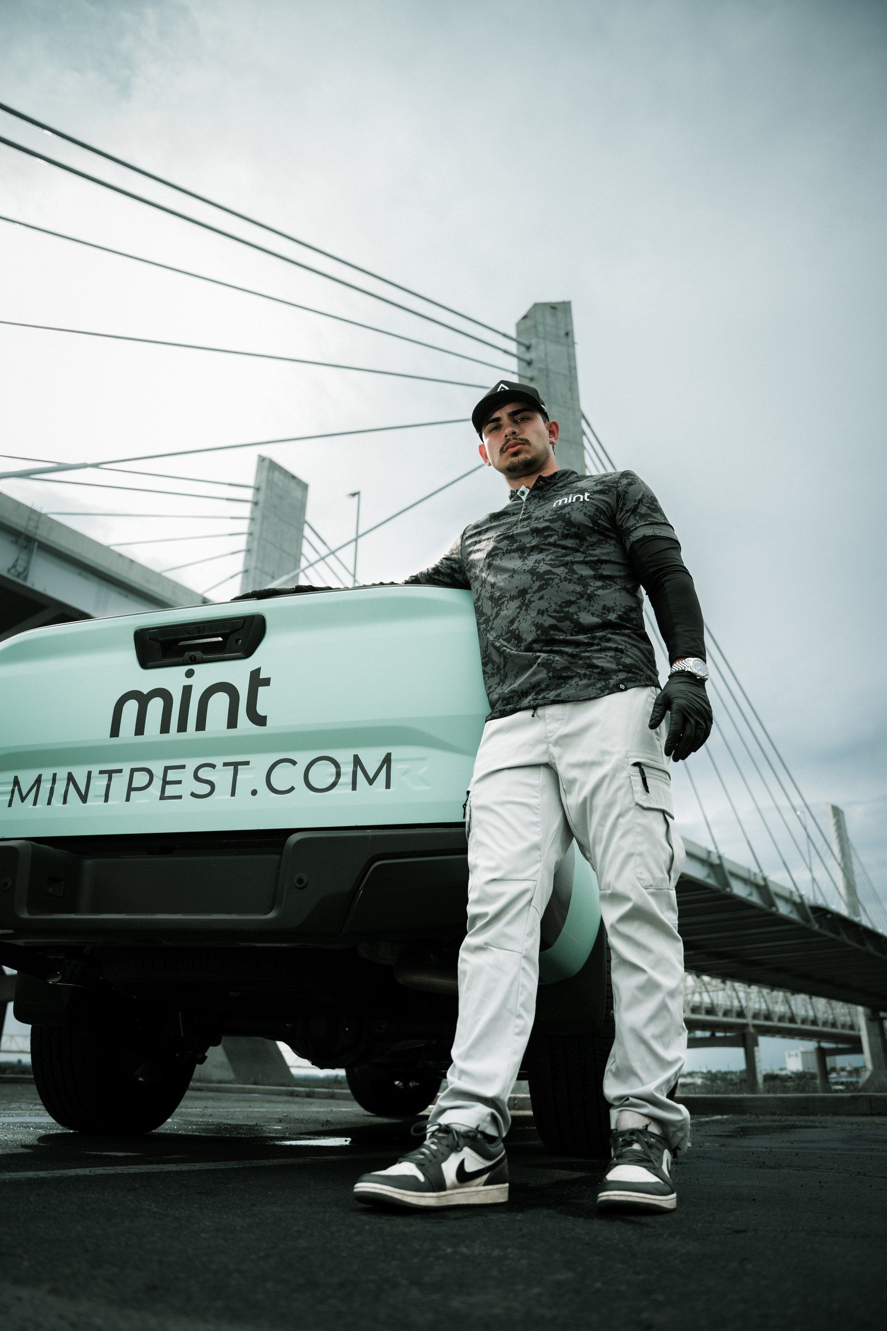 Technician standing by a branded pickup beneath a cable-stayed bridge