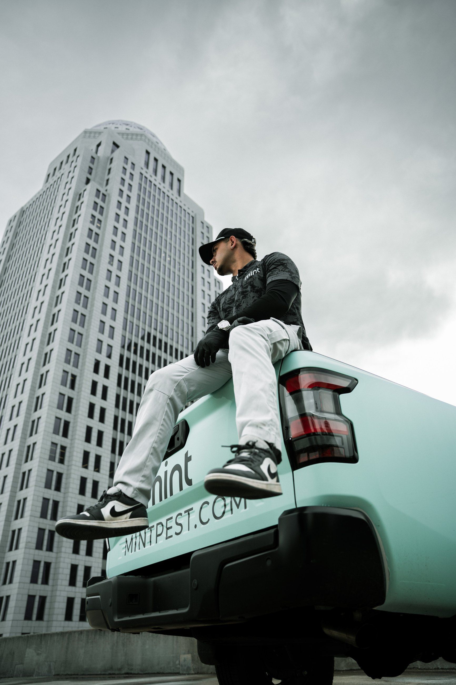 Technician on a truck tailgate beneath a glass skyscraper
