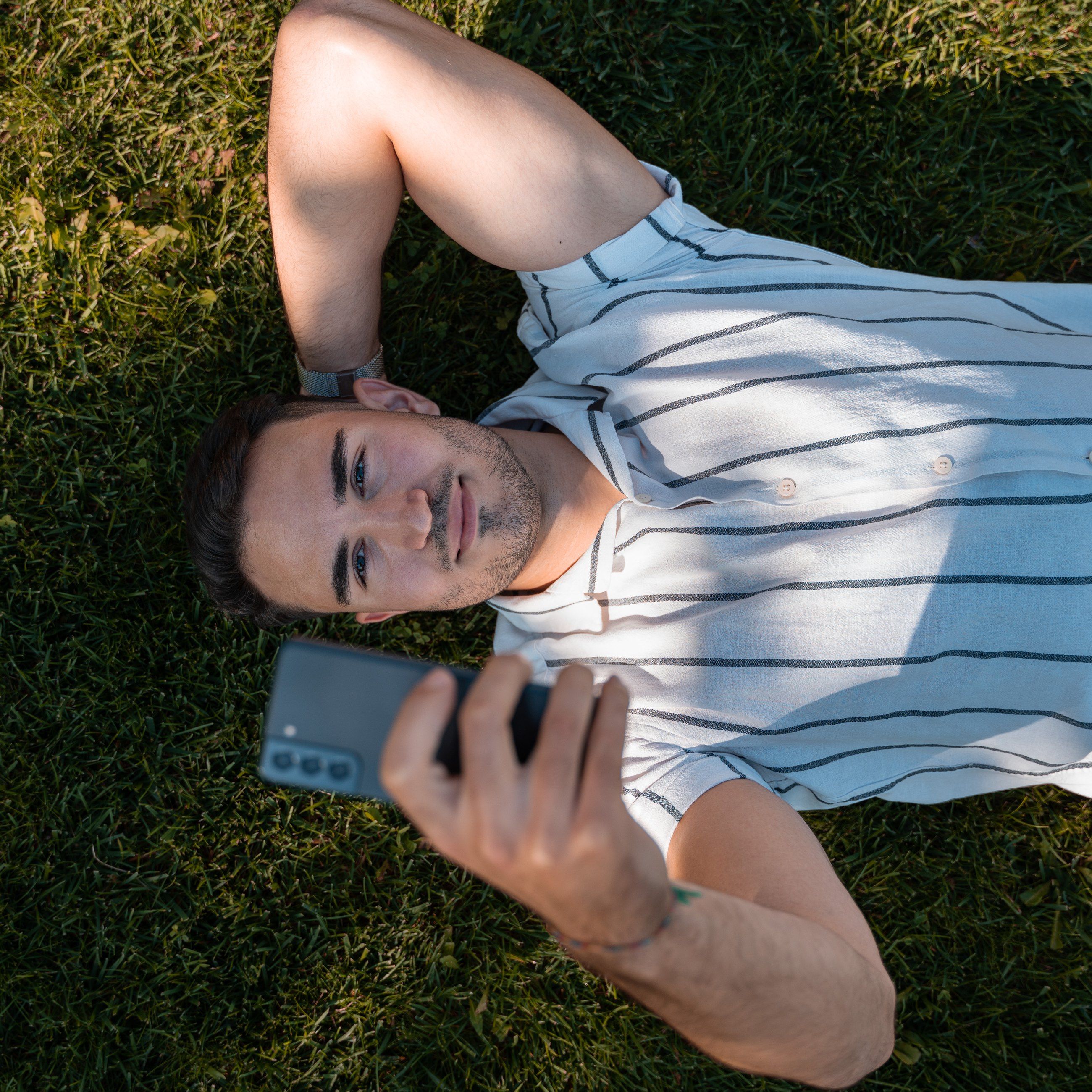 Man lying on the grass taking a selfie