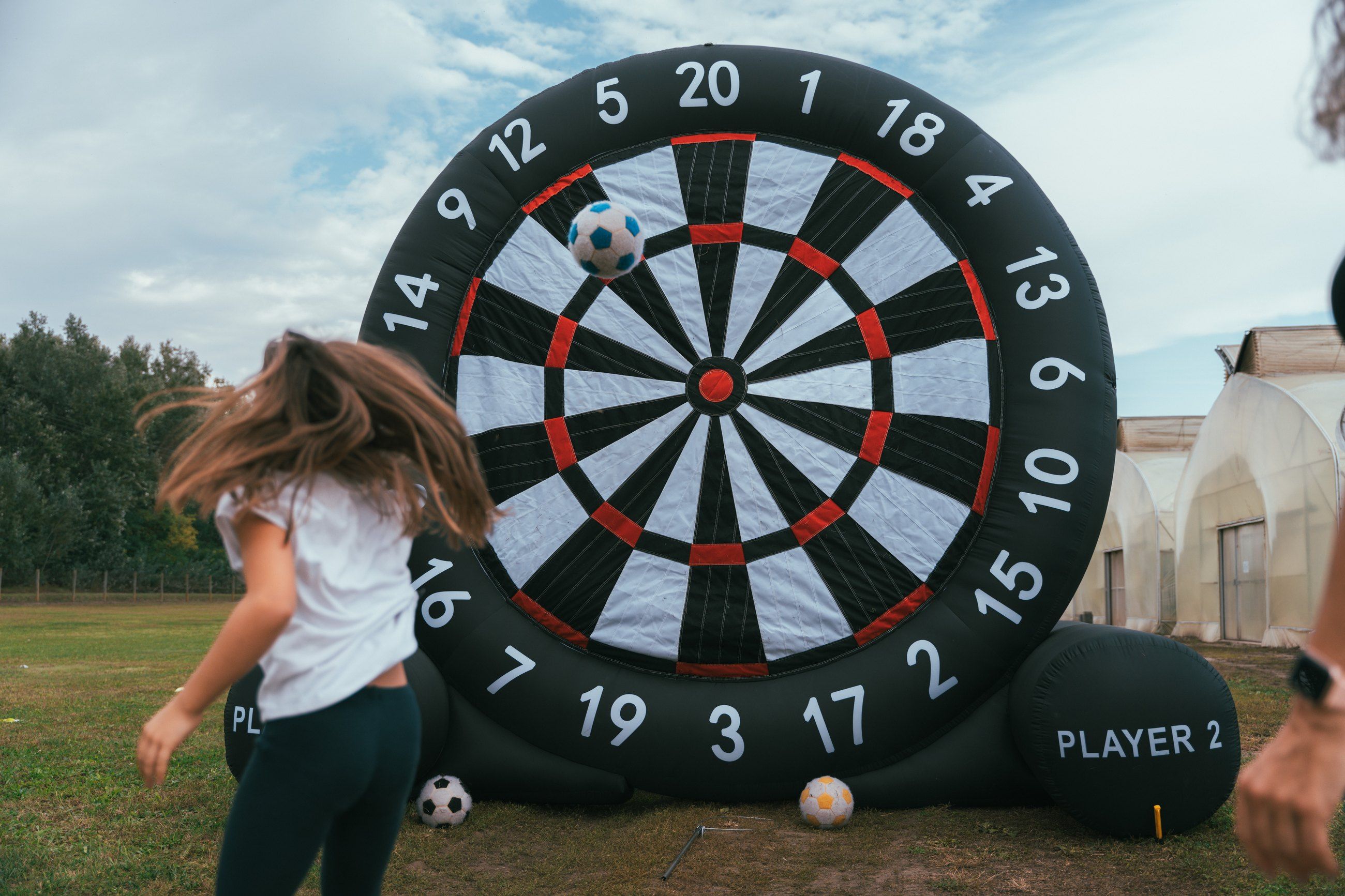 Child kicking a ball at a giant football dartboard