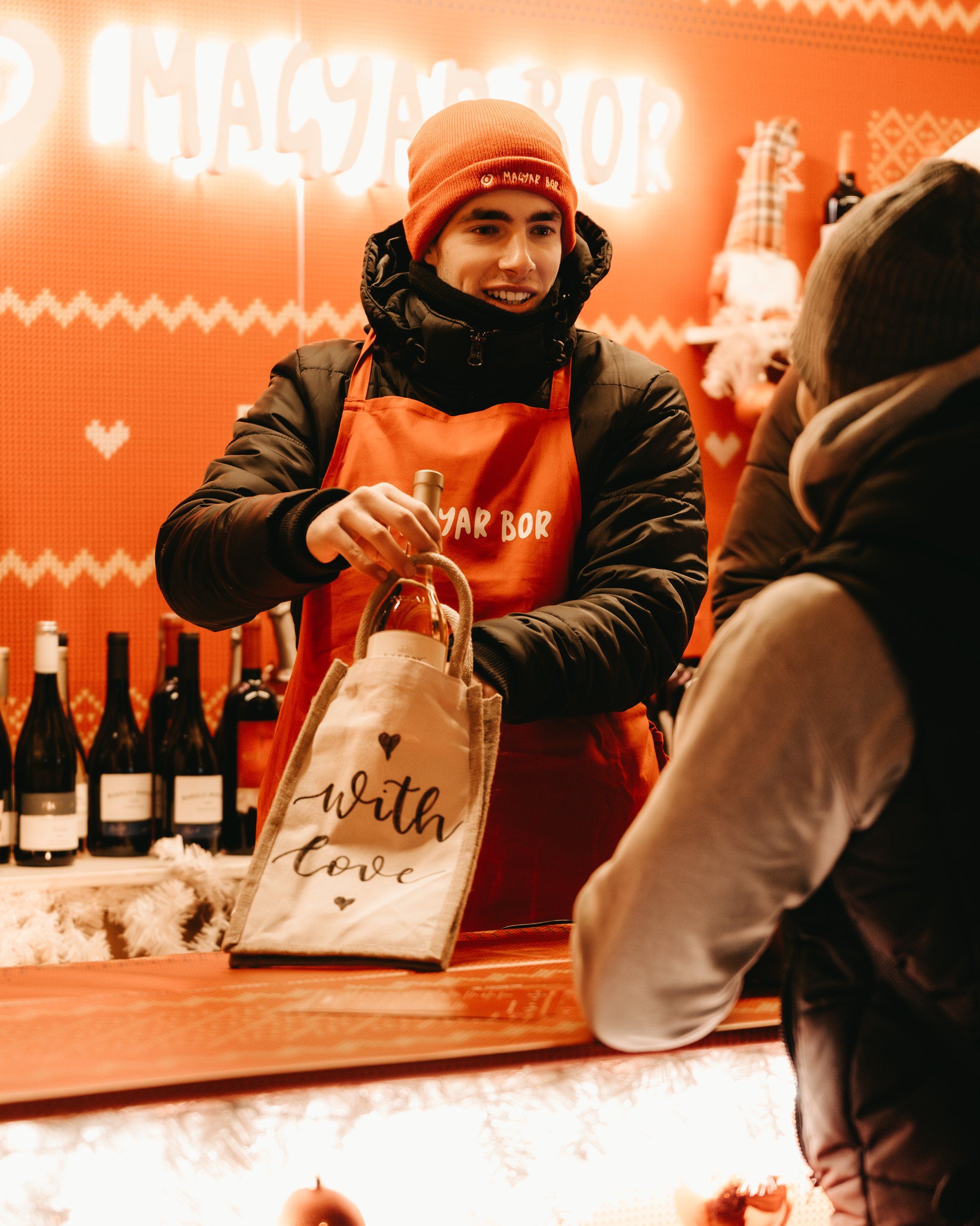 Stall staff handing over a hand-lettered wine bag