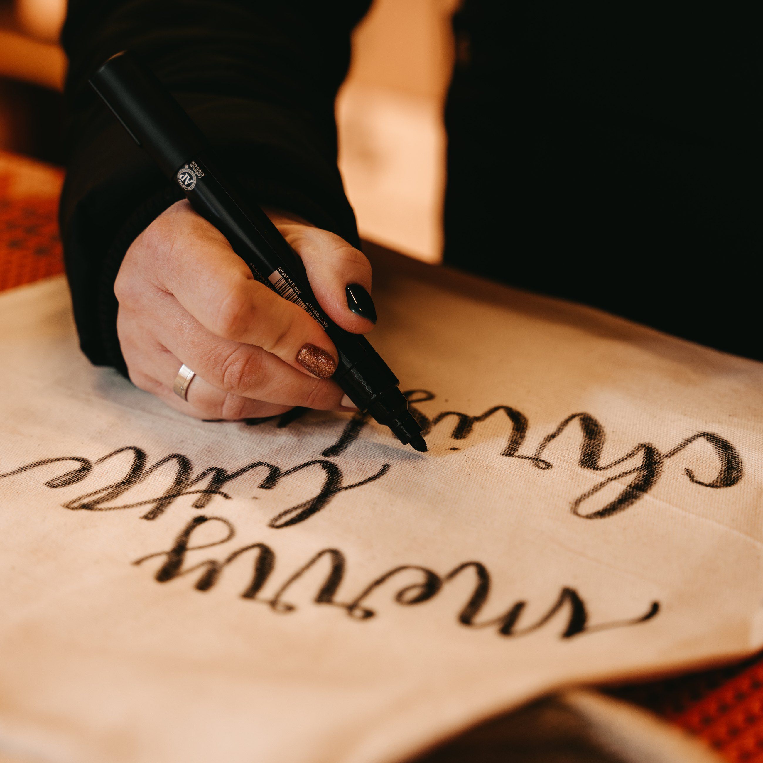 Hand-lettering a gift bag with "merry little Christmas"