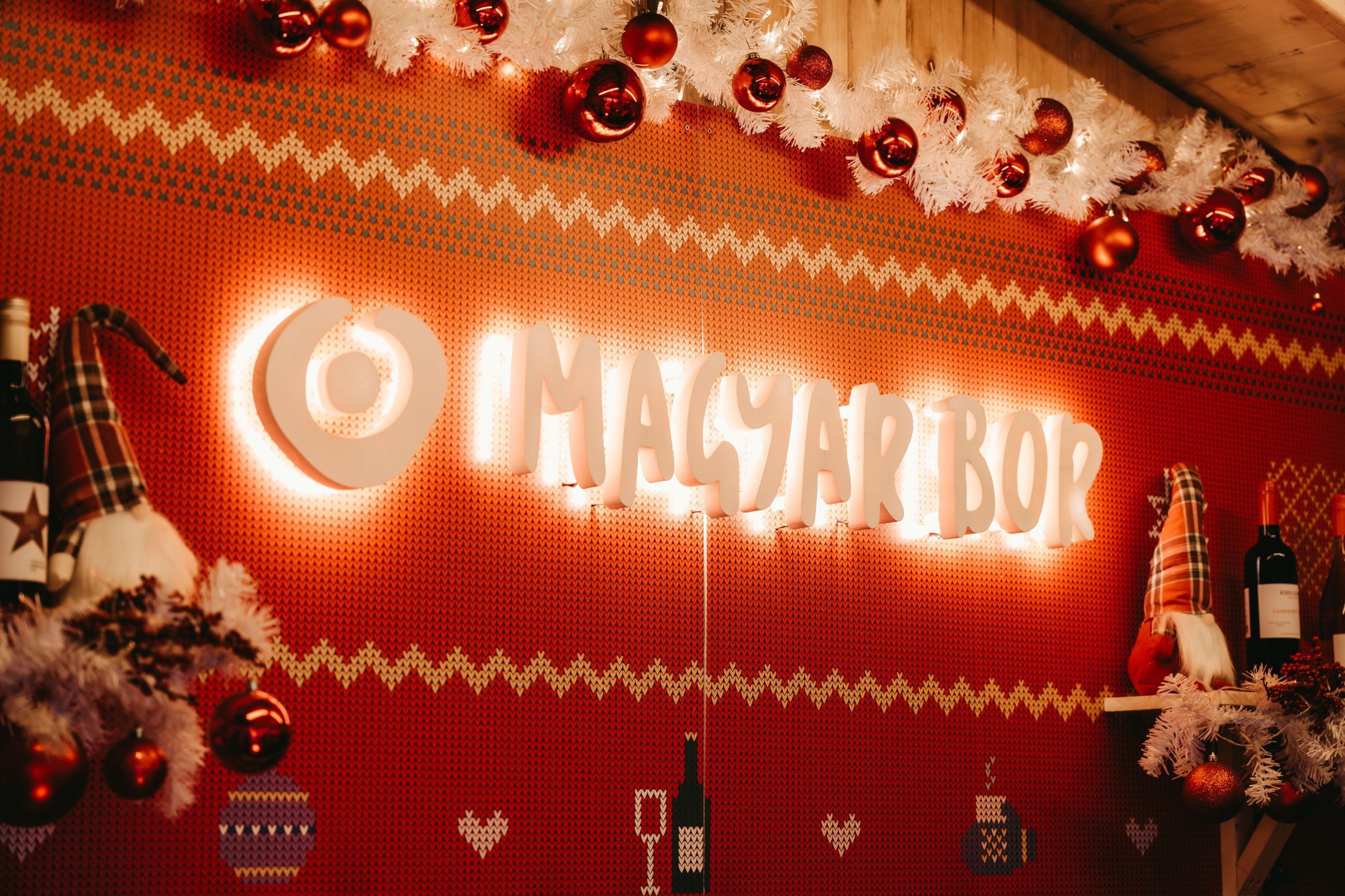 Glowing Magyar Bor sign above a festive wine stall